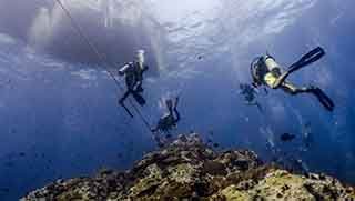 Advanced open water divers ascend from their deep dives to the boat