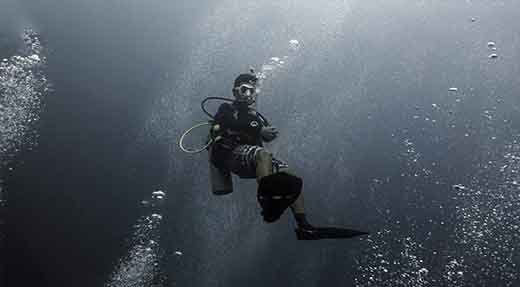 Advanced open water diver hovers in the middle of water surrounded with bubbles