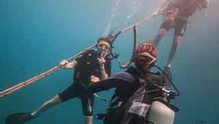 Discover Scuba Diving students descend with instructor