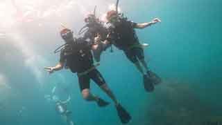 Discover Scuba Diving divers descend with instructor holding their tanks