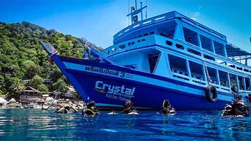 Scuba divers float on the blue water surface while diving boat wait for them to finish their Open water dives