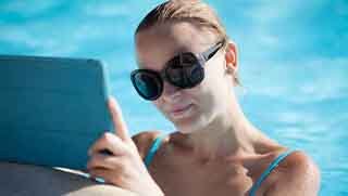 Blond women in the swimming pool reading Padi Open Water diver manual from a tablet