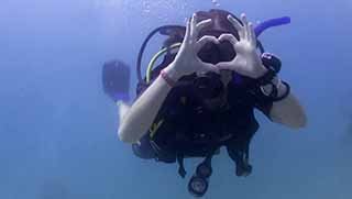 Open Water diver girl celebrate her certification on the surface next to dive boat